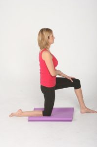 Blonde woman practicing corrective exercise by kneeling and stretching.