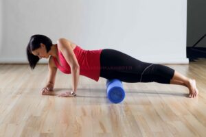 Woman lying on her side using a roller on her leg and hip.