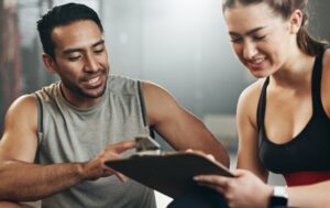 Two personal trainers looking at a clipboard discussing fitness insurance.