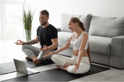 Man and woman looking at computer while holding a yoga pose